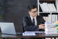 Young asian businessman working with financial data graph document stack on table to analyze financial reporting