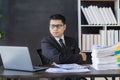 Young asian businessman working with financial data graph document stack on table to analyze financial reporting