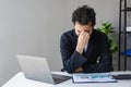 Young Asian businessman working on his laptop while having headache and anxiety Royalty Free Stock Photo