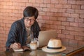 Young Asian businessman working with laptop in cafe