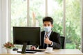 Young Asian businessmen wears a mask while working in the office. To protect himself from the spread of infectious coronavirus