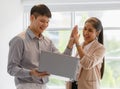 Young Asian businesspeople wearing smart casual standing and high five for congratulate happily during looking on a computer