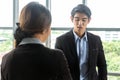 Young Asian Businessperson are standing and talking about financial business concept to agree on trade proposals within the modern Royalty Free Stock Photo