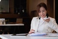 Young asian businesswoman beautiful charming smiling and talking on the mobile phone with speaker phone in the office Royalty Free Stock Photo