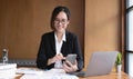 Young asian businesswoman beautiful charming smiling and using on mobile phone in the office. Royalty Free Stock Photo