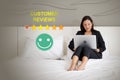 Young asian businesswoman in black suit perusing through customer reviews on her laptop while sitting comfortably on a bed in Royalty Free Stock Photo