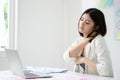 Young asian businesswoman feeling pain in neck after working