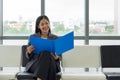 Young asian businesswoman in gray suit sit on a bench near the window, reading document in blue folder Royalty Free Stock Photo