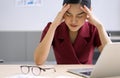 Young asian businesswoman holds her temple with both hands, sitting in the office. The concept of unemployed, sadness, depressed Royalty Free Stock Photo