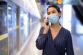 Young Asian businesswoman with mask talking on the phone at the subway train station Royalty Free Stock Photo