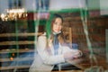 Young Asian businesswoman with mask using phone and sitting with distance outside the coffee shop Royalty Free Stock Photo