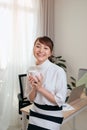 Young Asian businesswoman sitting on the desk while holding coffee cup in her office Royalty Free Stock Photo