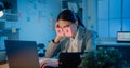 Young Asian businesswoman sitting on desk overworked tired sleep over a laptop at office at night. Exhausted burnout lady with two Royalty Free Stock Photo