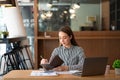 A young Asian businesswoman stands in front of her desk holding a smirked tablet. money business idea Royalty Free Stock Photo