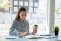 A young Asian businesswoman stands in front of her desk holding a smirked tablet. money business idea Royalty Free Stock Photo