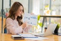 A young Asian businesswoman stands in front of her desk holding a smirked tablet. money business idea Royalty Free Stock Photo