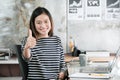 Young asian businesswoman thump up and smiling while sitting at