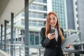 A young Asian businesswoman wearing a suit holding files standing in a big city waling on the street. Young Asian Royalty Free Stock Photo