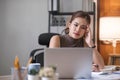 Young Asian businesswoman working on laptop computer, stressed has a headache and thinks hard from work at the office. Royalty Free Stock Photo