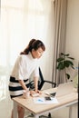 Young Asian businesswoman working with laptop and standing behind the desk at home Royalty Free Stock Photo