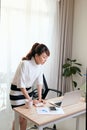 Young Asian businesswoman working with laptop and standing behind the desk at home Royalty Free Stock Photo