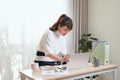 Young Asian businesswoman working with laptop and standing behind the desk at home Royalty Free Stock Photo