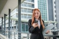 A young Asian businesswomen wearing a suit holding files standing in a big city on a busy downtown street. Young Asian Royalty Free Stock Photo