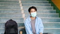 Young asian campus student man wearing protection mask smiling and looking at camerawhile sitting in campus, coronavirus Royalty Free Stock Photo