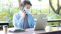 Young asian campus student man wearing protection mask talking moblie phone and working with laptop computer while online study in Royalty Free Stock Photo