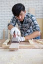 Young asian carpenter polishing wooden job with sanding machine Royalty Free Stock Photo