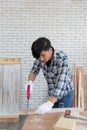Young asian carpenter sawing wooden job with handsaw