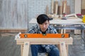 Young asian carpenter working on wooden job with spirit level Royalty Free Stock Photo
