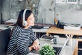 Young asian casual businesswoman arm on desk rest pose with laptop computer and listening music via headphone and looking through Royalty Free Stock Photo