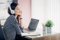 Young asian casual businesswoman arm on desk rest pose with laptop computer and listening music via headphone and looking through Royalty Free Stock Photo