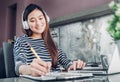 Young asian casual businesswoman listening music and writing rep Royalty Free Stock Photo