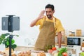 Young asian young chef who is good at cooking, love cook, standing live via online app in kitchen, was standing there talking