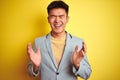 Young asian chinese businessman wearing jacket standing over  yellow background celebrating mad and crazy for success with Royalty Free Stock Photo