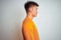 Young asian chinese man wearing orange sweater standing over isolated white background looking to side, relax profile pose with Royalty Free Stock Photo