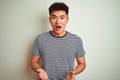 Young asian chinese man wearing striped t-shirt standing over isolated white background afraid and shocked with surprise Royalty Free Stock Photo