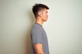 Young asian chinese man wearing striped t-shirt standing over isolated white background looking to side, relax profile pose with Royalty Free Stock Photo