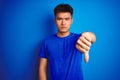 Young asian chinese man wearing t-shirt standing over isolated blue background looking unhappy and angry showing rejection and Royalty Free Stock Photo