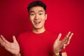 Young asian chinese man wearing  t-shirt standing over isolated red background very happy and excited, winner expression Royalty Free Stock Photo