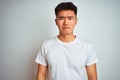 Young asian chinese man wearing t-shirt standing over isolated white background depressed and worry for distress, crying angry and Royalty Free Stock Photo