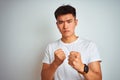 Young asian chinese man wearing t-shirt standing over isolated white background Ready to fight with fist defense gesture, angry Royalty Free Stock Photo