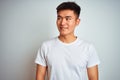 Young asian chinese man wearing t-shirt standing over isolated white background smiling looking to the side and staring away Royalty Free Stock Photo