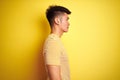 Young asian chinese man wearing t-shirt standing over isolated yellow background looking to side, relax profile pose with natural Royalty Free Stock Photo