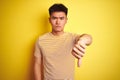 Young asian chinese man wearing t-shirt standing over isolated yellow background looking unhappy and angry showing rejection and Royalty Free Stock Photo