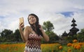 Young Asian Chinese tourist woman taking self portrait selfie photo with mobile phone on excursion through beautiful flowers field Royalty Free Stock Photo