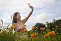 Young Asian Chinese tourist woman taking self portrait selfie photo with mobile phone on excursion through beautiful flowers field Royalty Free Stock Photo