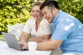 Young Asian chubby couple using a laptop in the outdoors green park together. Happy smiling man and woman working Royalty Free Stock Photo